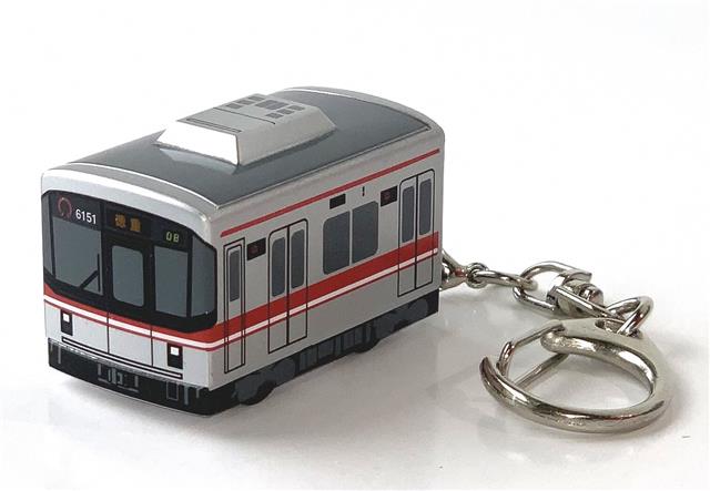 電車型キーホルダー写真。金色の車体に赤いラインが入った電車です。